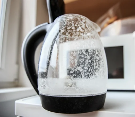 En glaskanna täckt av vita fläckar från kalk. Vi utför avkalkning och service på Gotland.